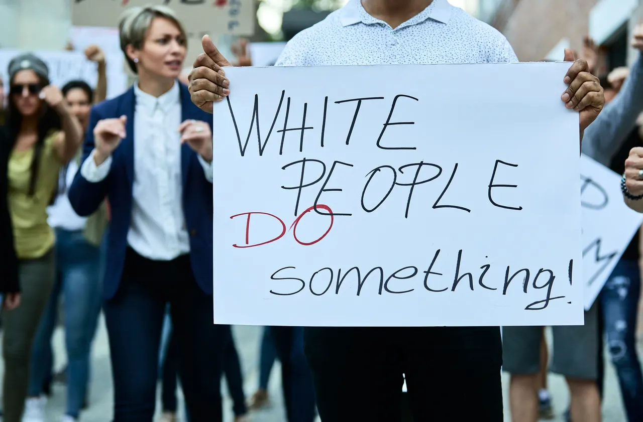 People waking in a rally with a banner “White people do something”